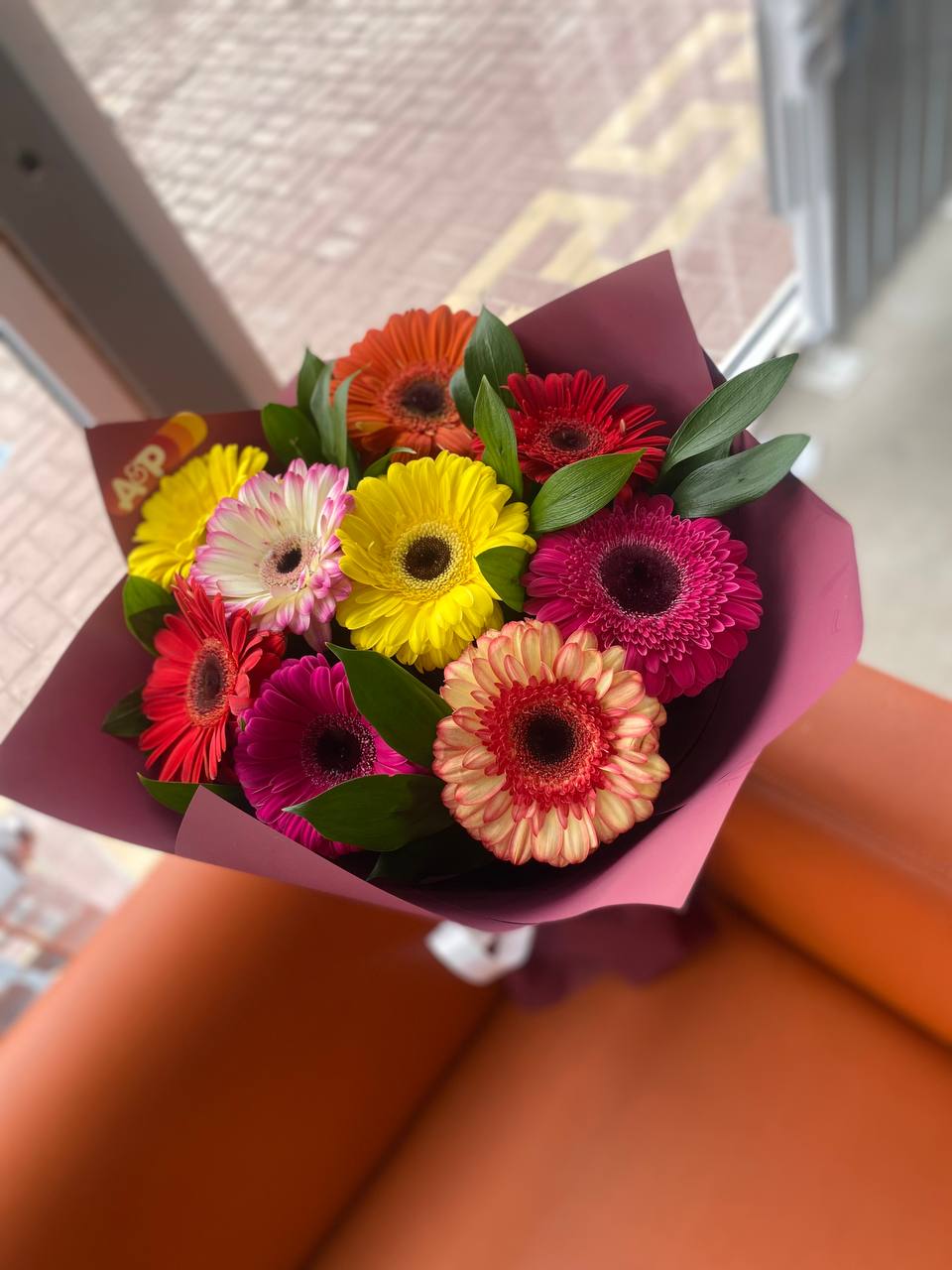 Герберы 9 шт с зеленью в красивой упаковке.